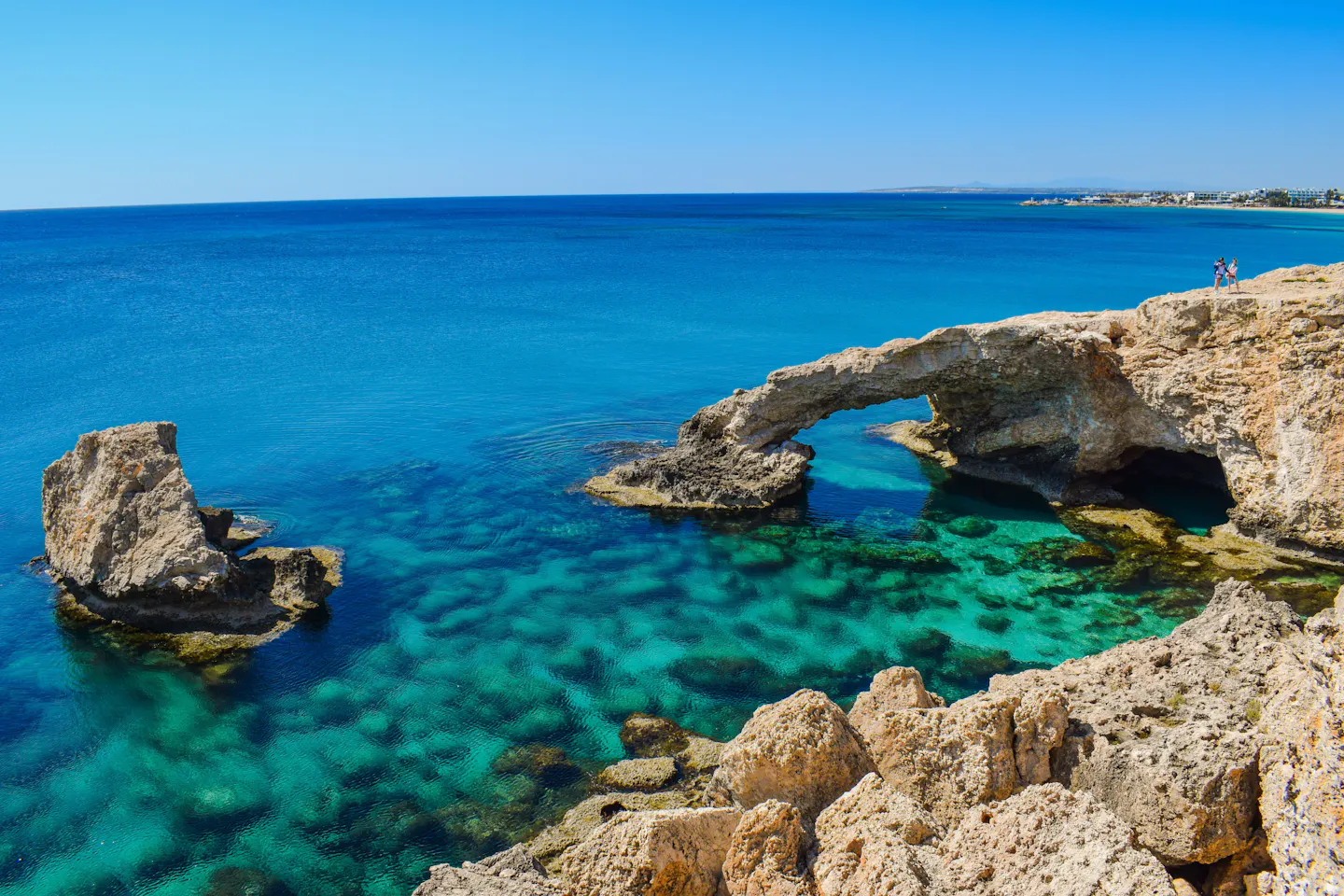 A natural limestone sea arch above clear emerald and turquoise water on the coast of Cyprus