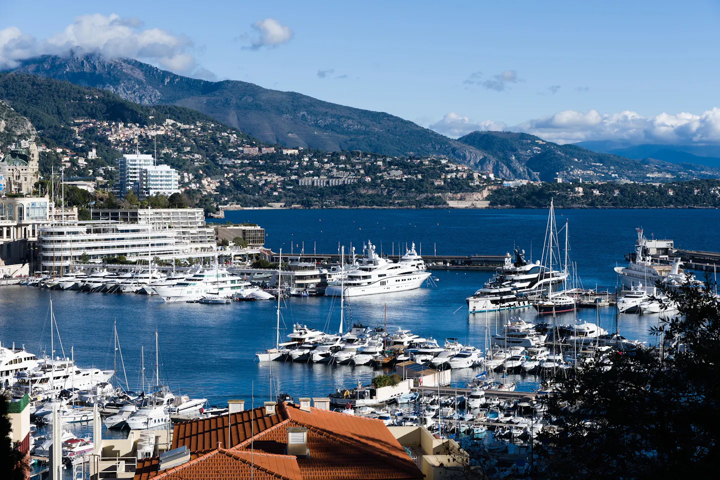 Superyachts and sailing boats moored in Monaco's harbour below the Riviera hills