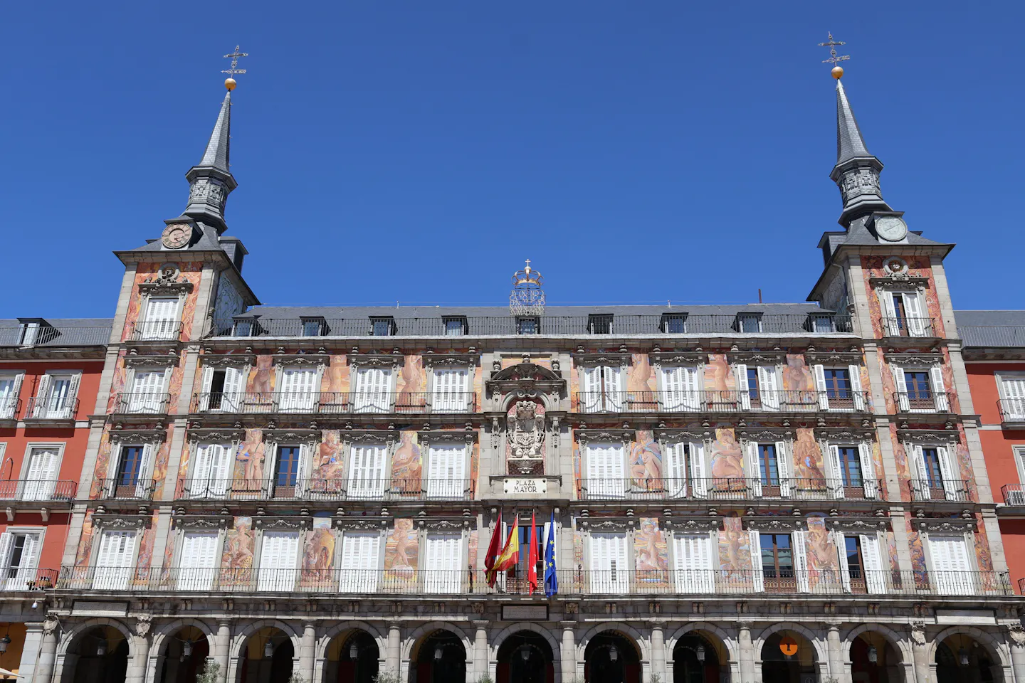 The frescoed facade and twin spires of the Casa de la Panaderia on Plaza Mayor under a deep blue sky
