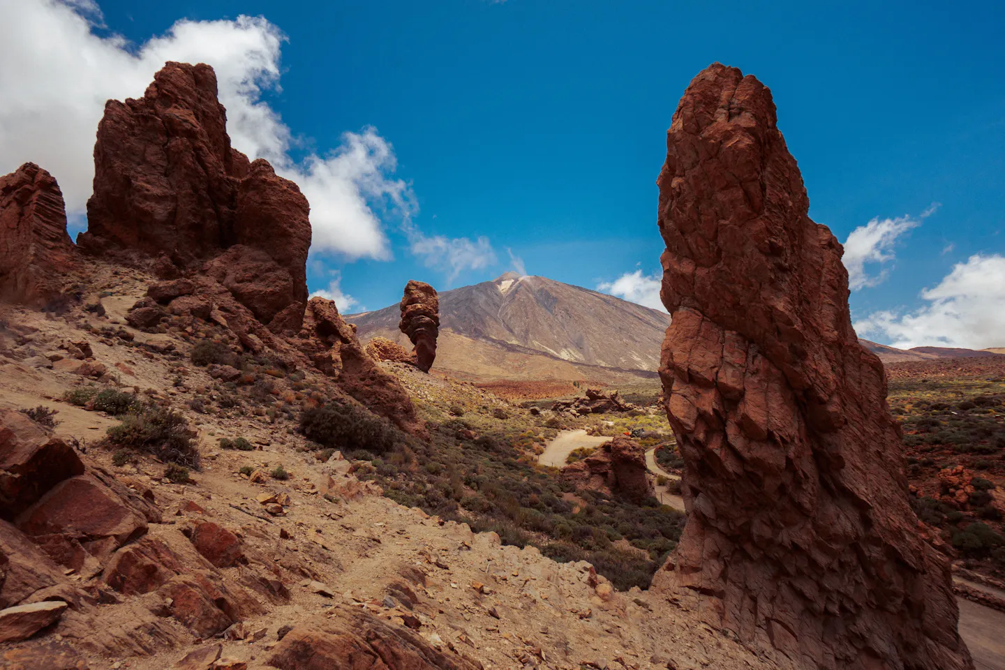 Red volcanic rock towers in Teide National Park, Tenerife, with Mount Teide rising under a bright blue sky