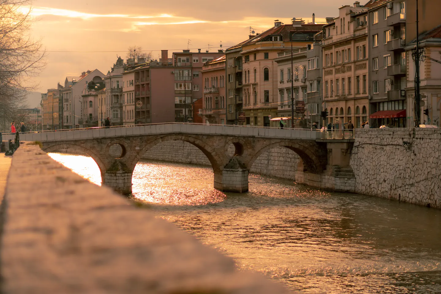 The stone arches of the Latin Bridge over the Miljacka river in Sarajevo in golden evening light