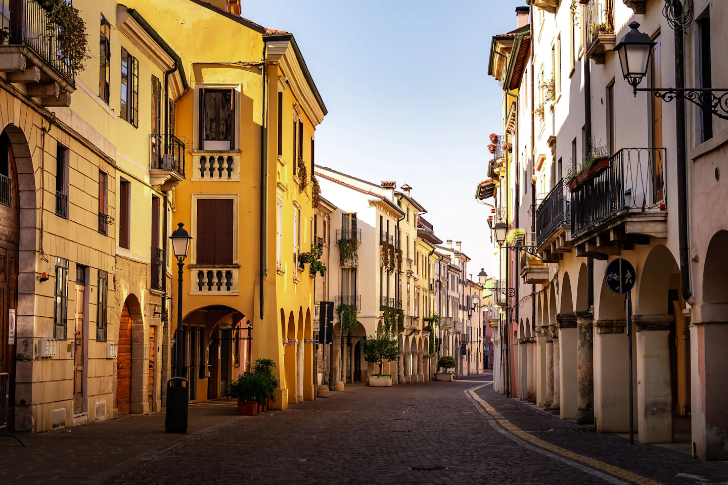 An empty arcaded street in an Italian old town with early morning sun on ochre facades