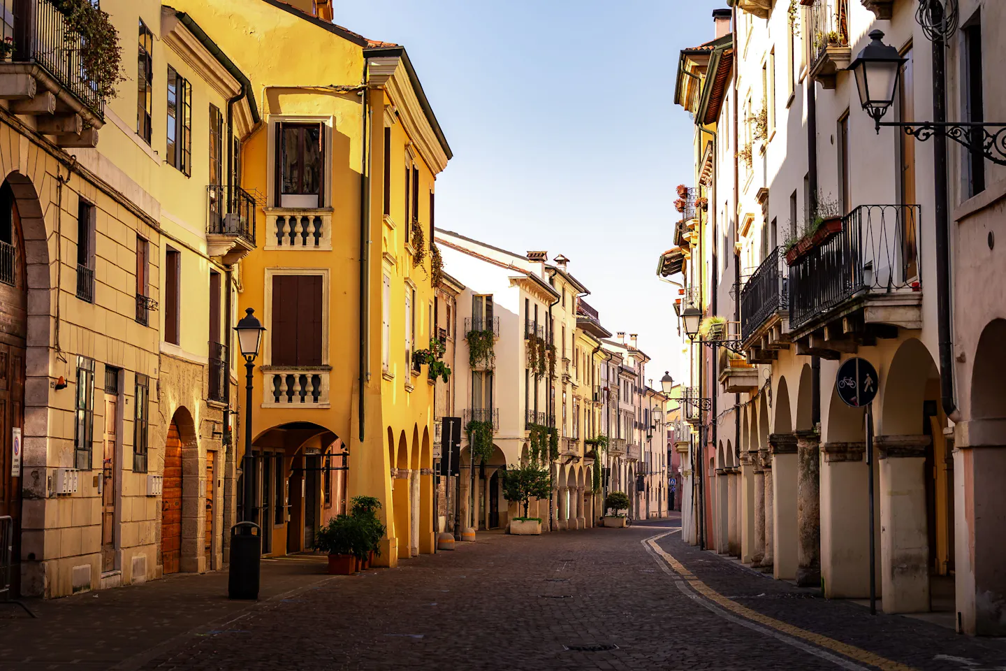 An empty arcaded street in an Italian old town with early morning sun on ochre facades