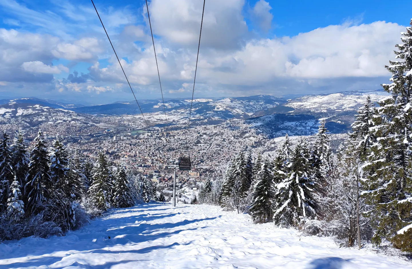 Winter view over Sarajevo from Trebević, with snow-covered slopes and cable-car lines