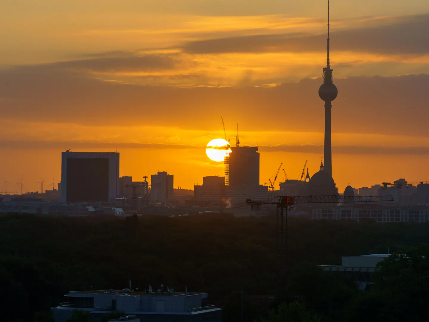 The sun setting behind Berlin's skyline with the Fernsehturm silhouetted against an orange sky
