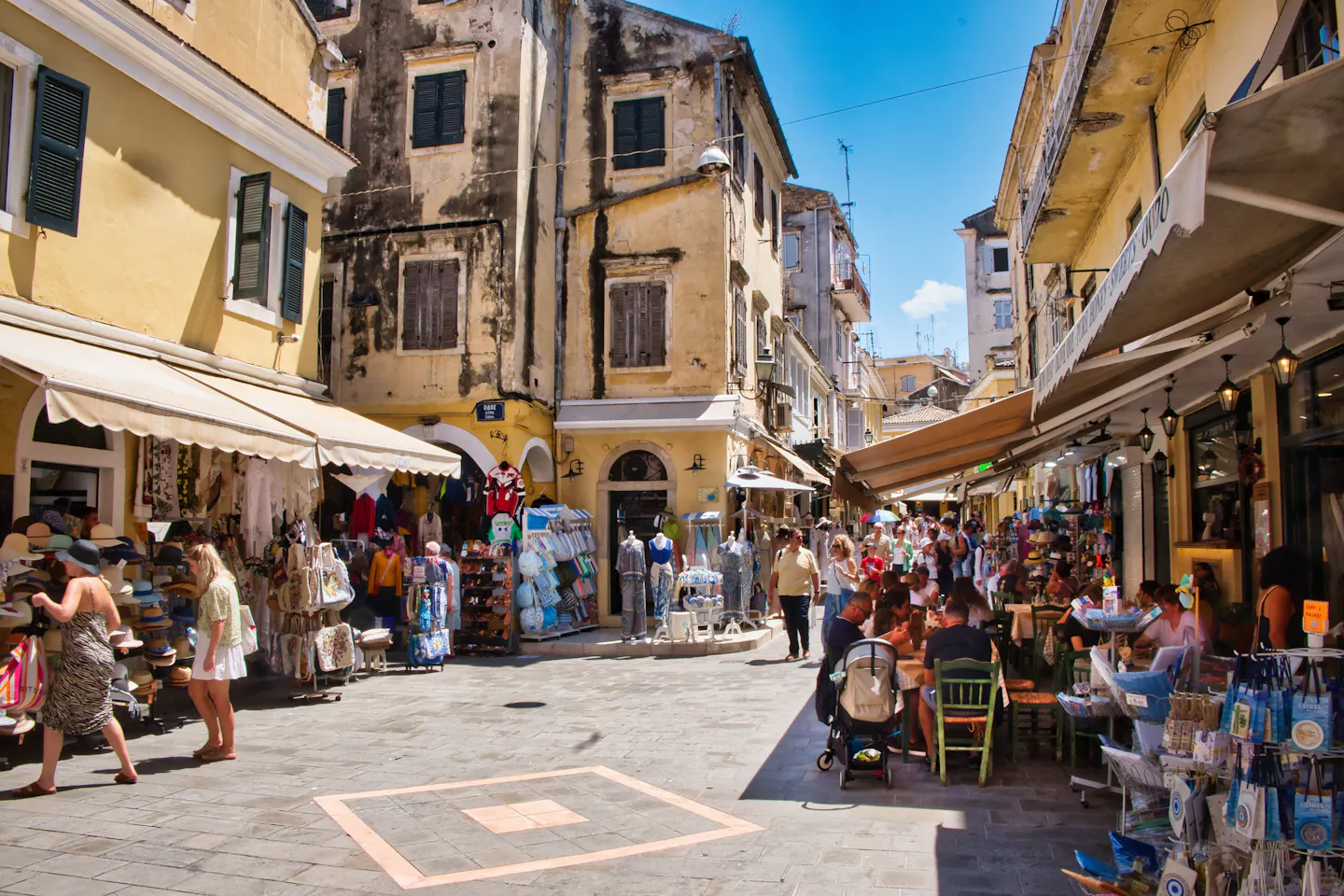 Sunny pedestrian street with cafés and shops in Corfu Old Town, Greece