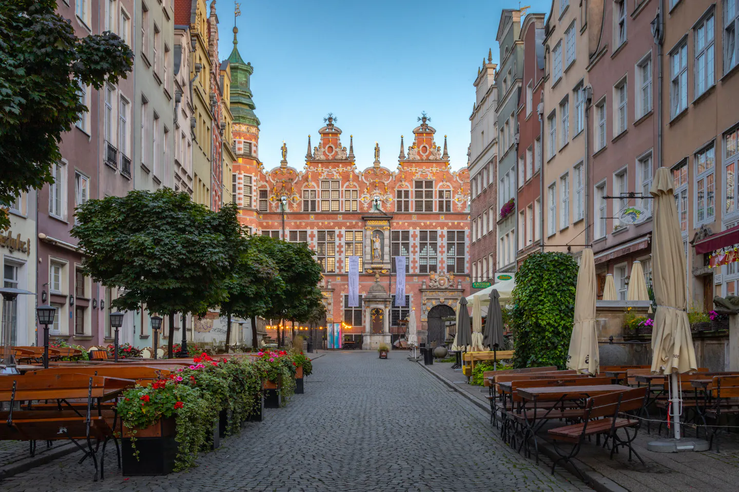 A cobbled pedestrian street lined with cafés and flower planters in Gdańsk's old town