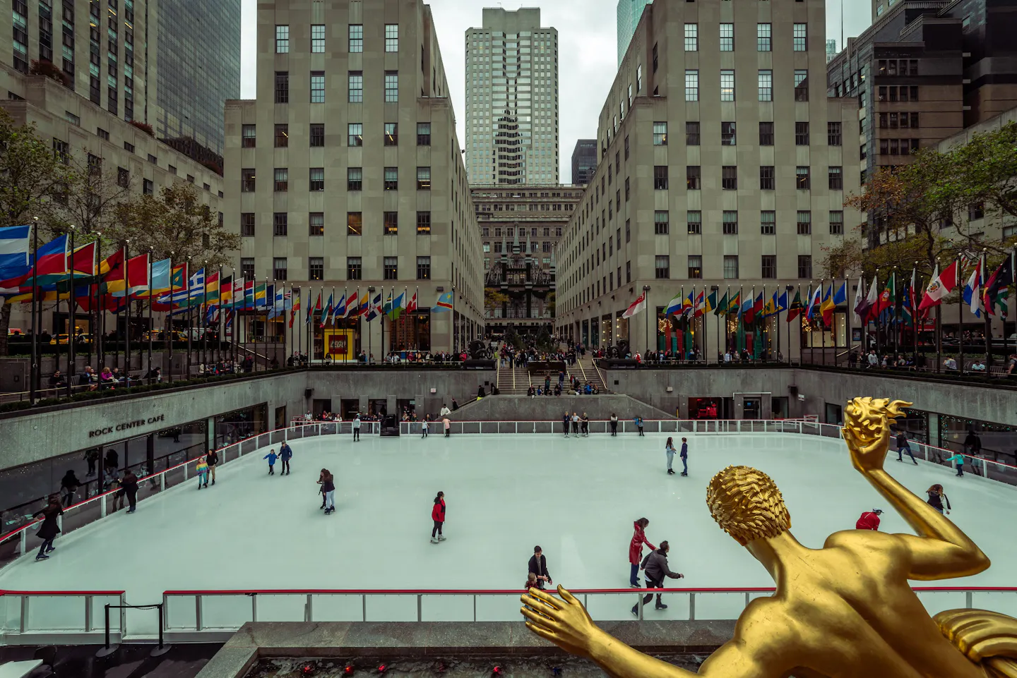 New York City, USA’s Rockefeller Center ice rink with skaters and the Prometheus statue.