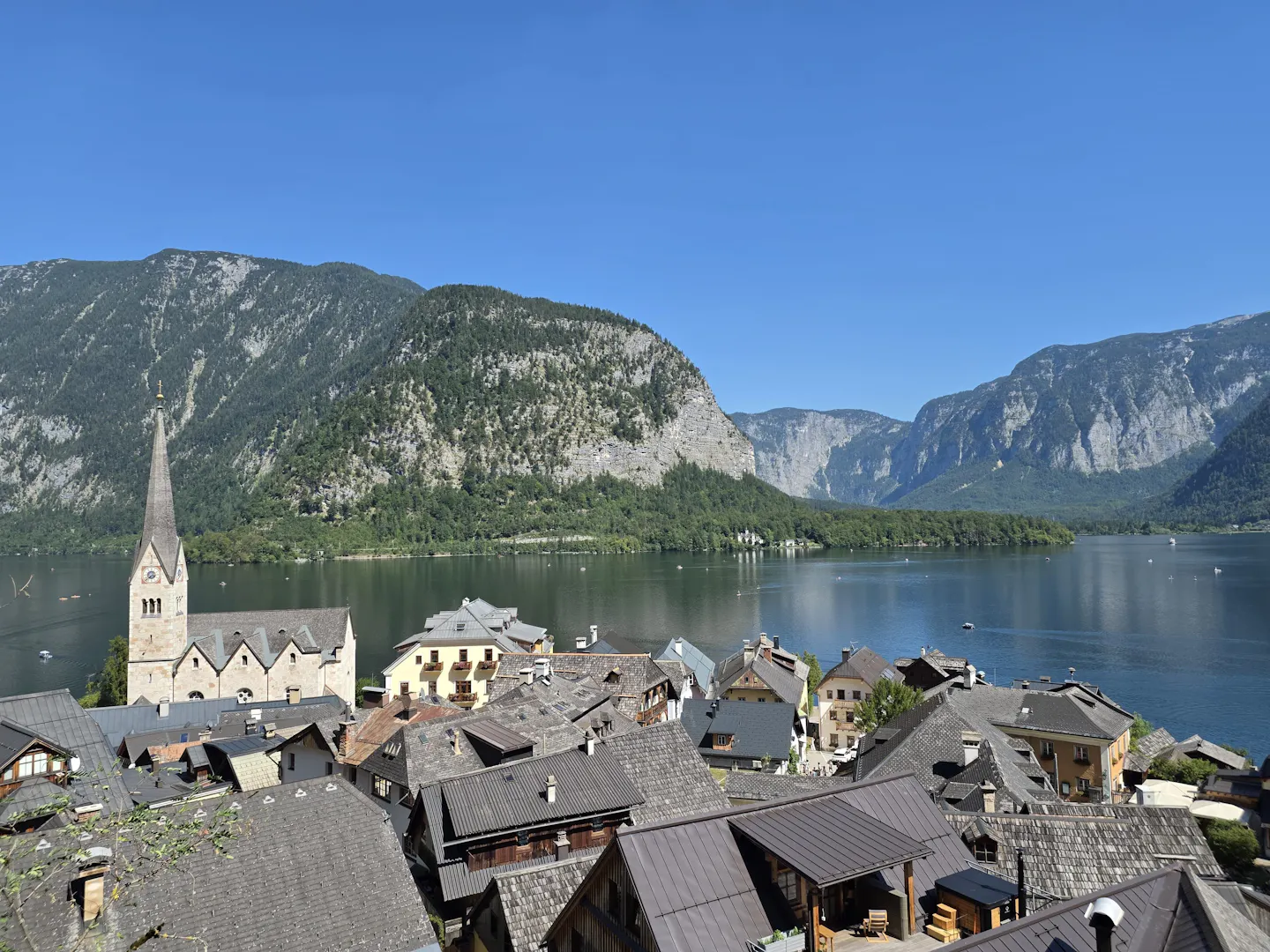 Hallstatt's rooftops and church beside a calm alpine lake with steep mountains beyond