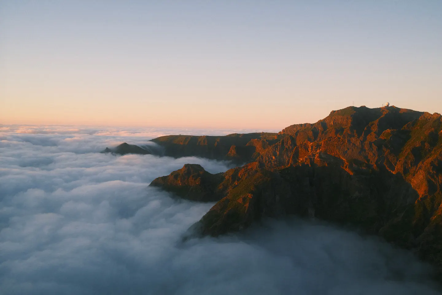 Madeira mountain ridges lit by low sun above a sea of cloud