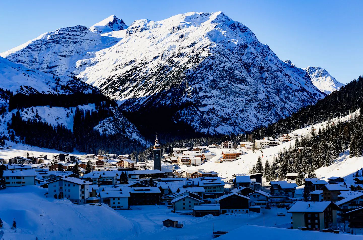 Snow-covered Lech am Arlberg village beneath the Austrian Alps, with its church tower in the valley