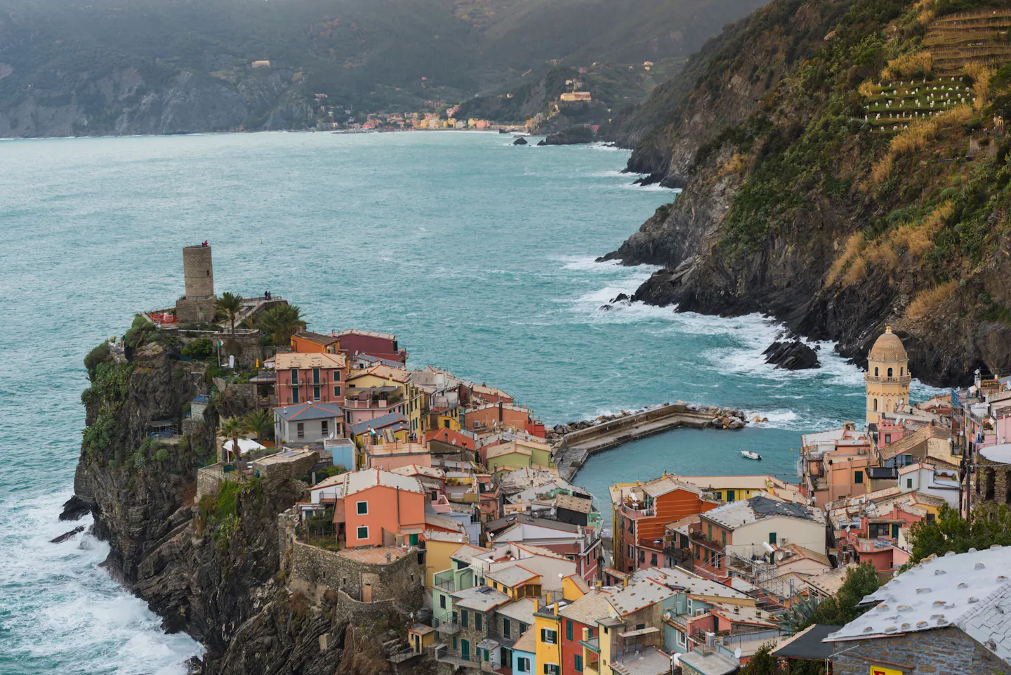 The pastel houses and small harbour of Vernazza on its rocky headland above the Ligurian sea