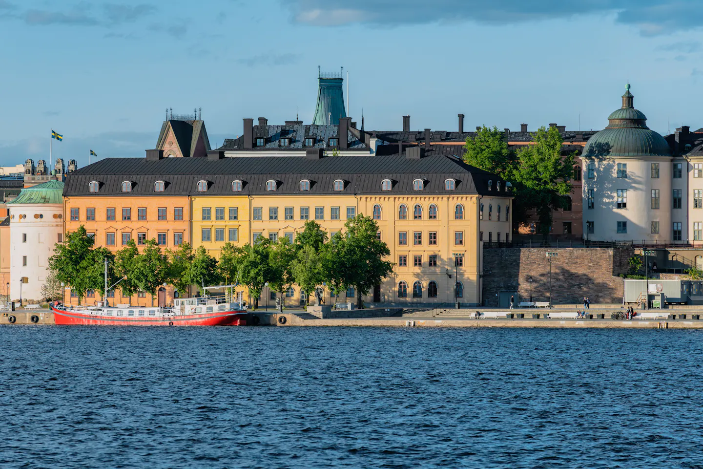 Ochre and yellow waterfront buildings on the Stockholm shoreline above dark blue water