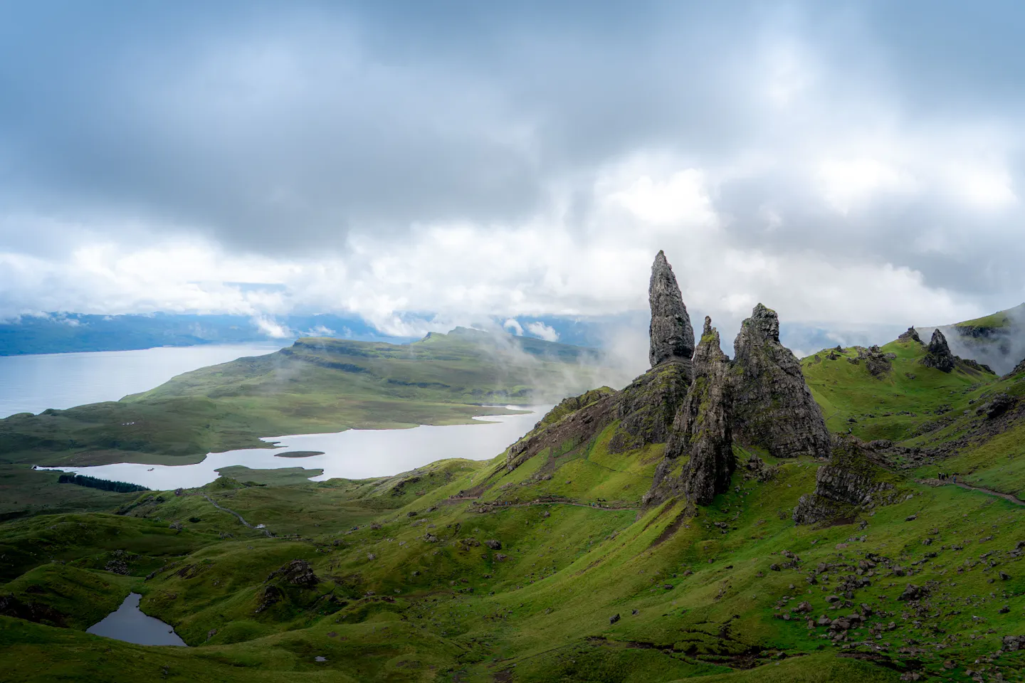 The Old Man of Storr rock pinnacles above green slopes and lochs on the Isle of Skye