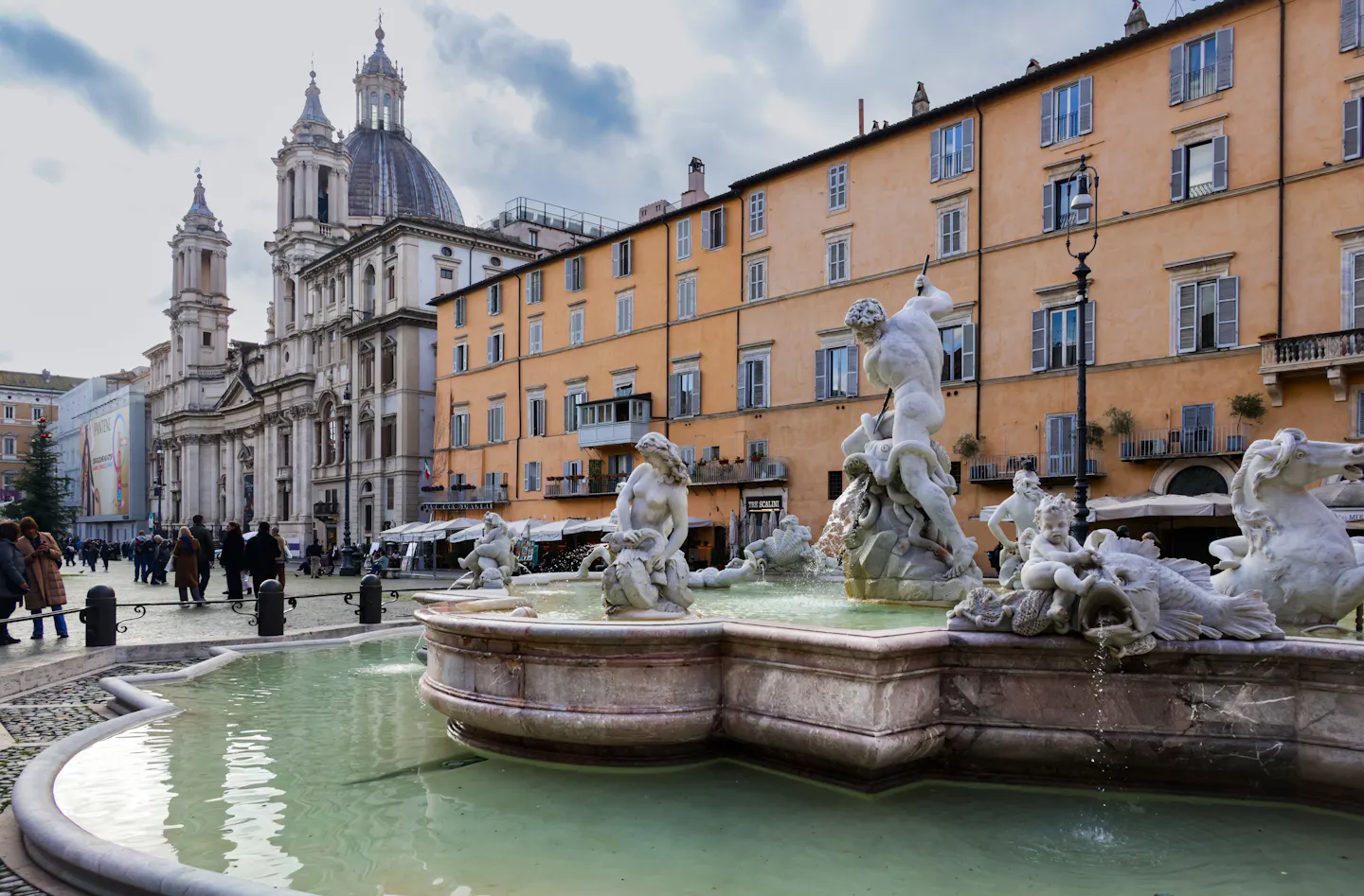 Piazza Navona in Rome's historic centre: the Fountain of Neptune in the foreground, ochre palazzi along the square and the dome and towers of Sant'Agnese in Agone