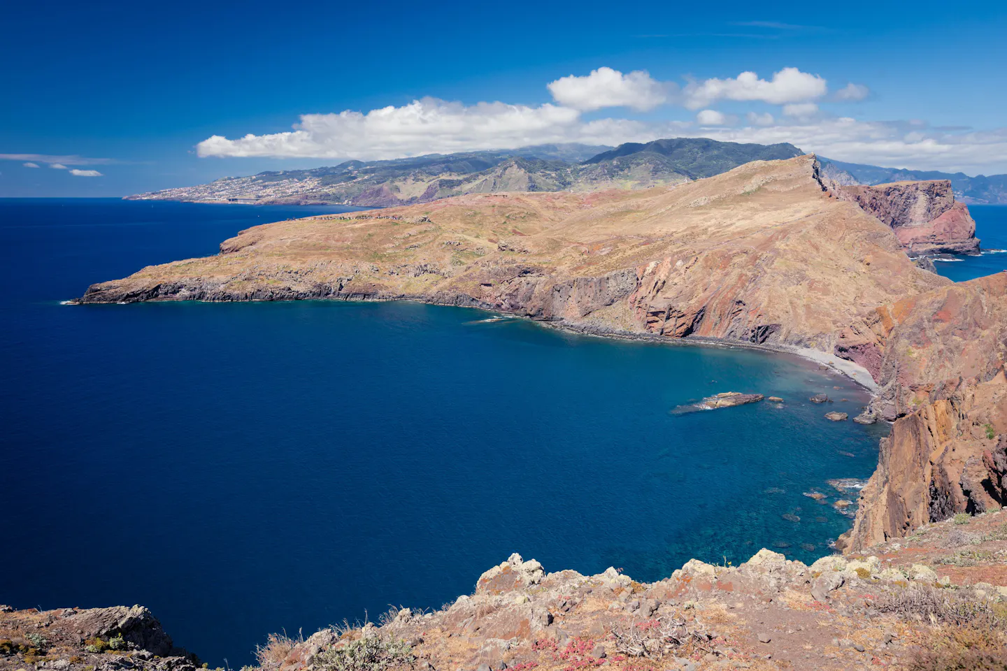 Barren volcanic headland curving into deep blue Atlantic water on the east coast of Madeira