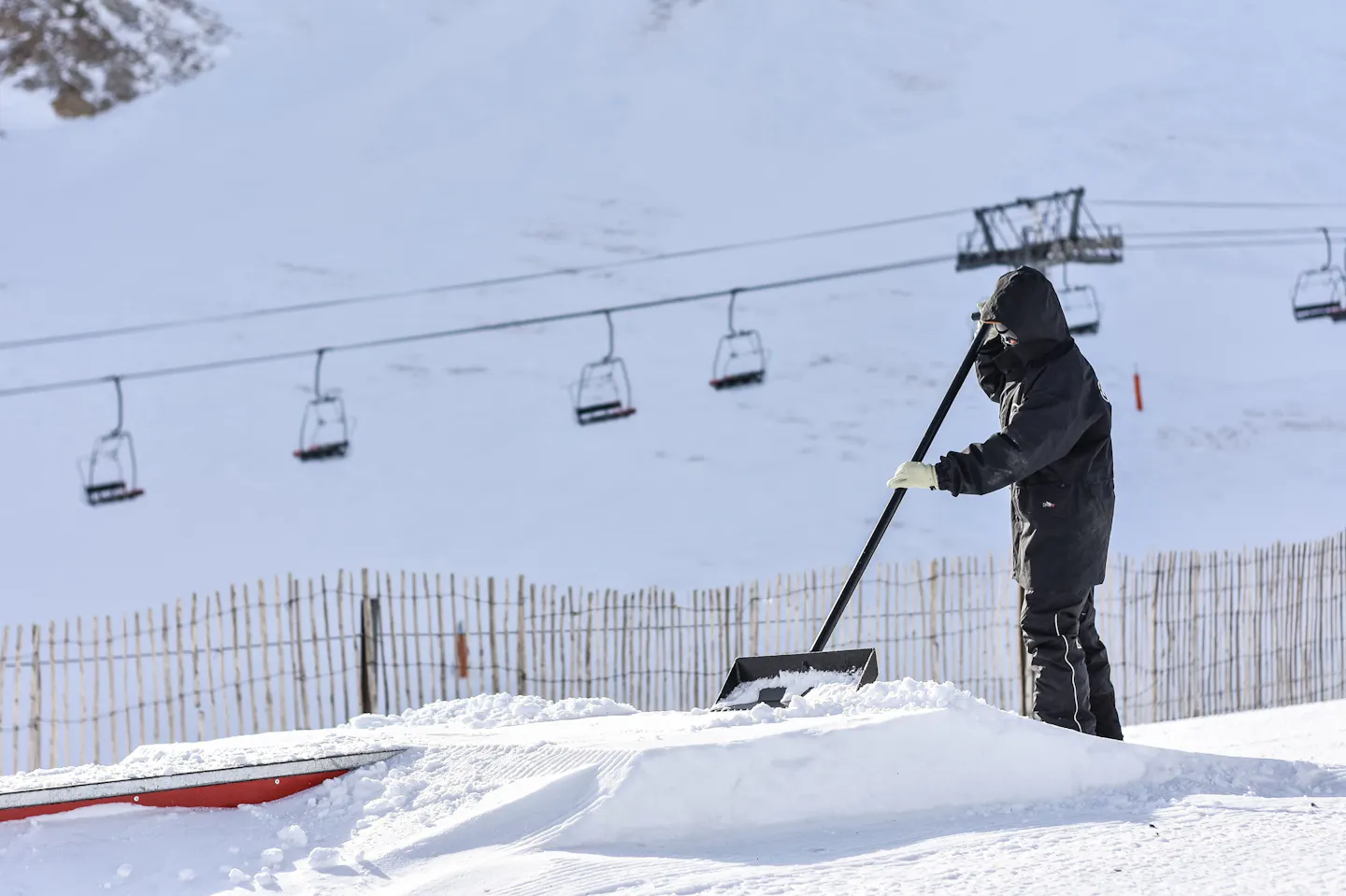 Pal Arinsal ski resort in winter, with a worker clearing snow beneath the ski lift