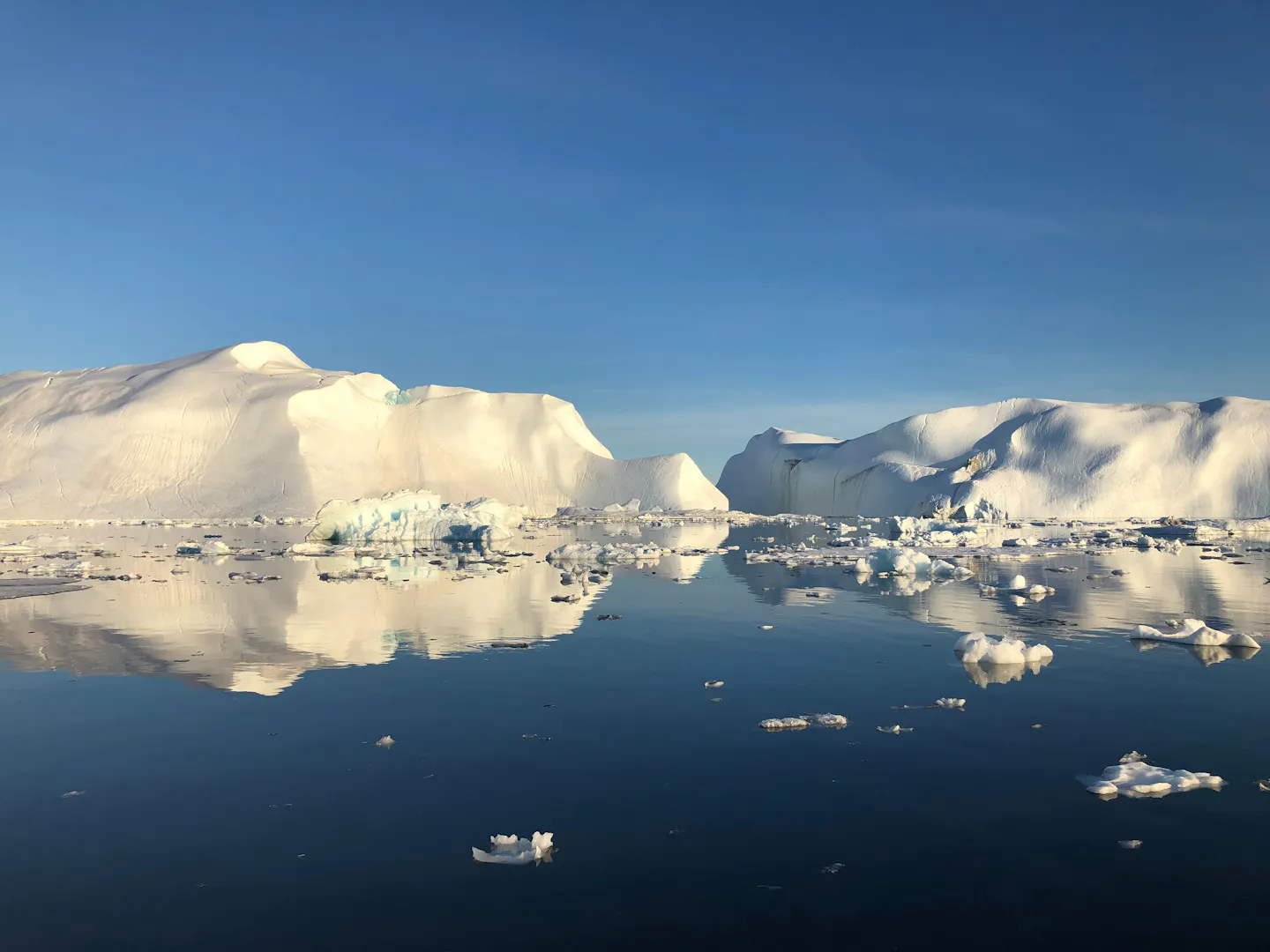 Icebergs reflected in calm water near Ilulissat, Greenland