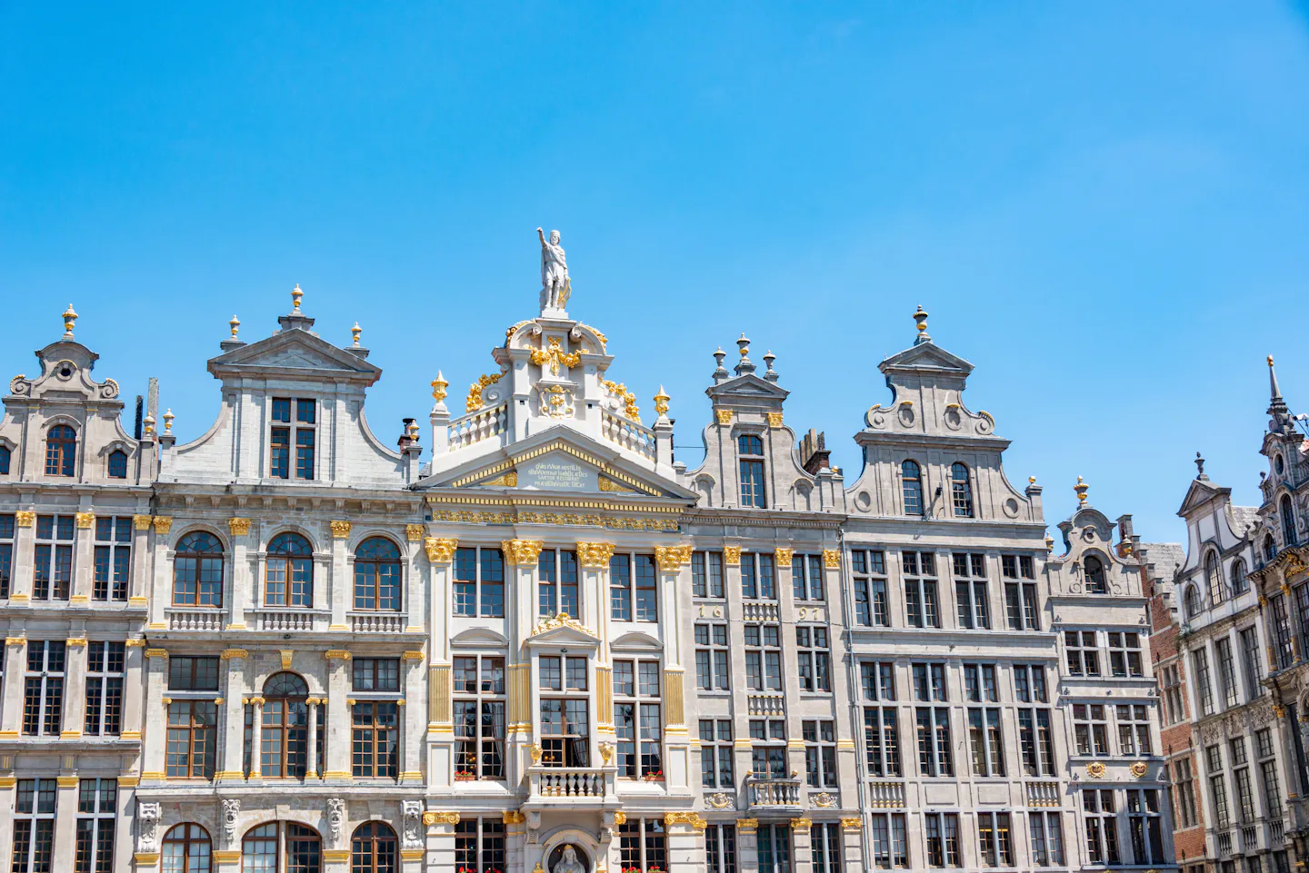 The gilded baroque guild houses of Brussels' Grand Place against a clear blue sky