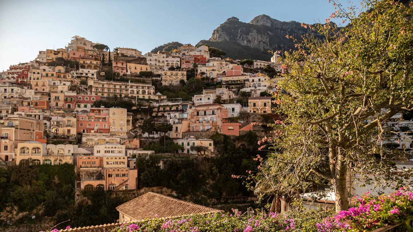 The pastel houses of Positano stacked up the cliff in golden evening light on the Amalfi Coast