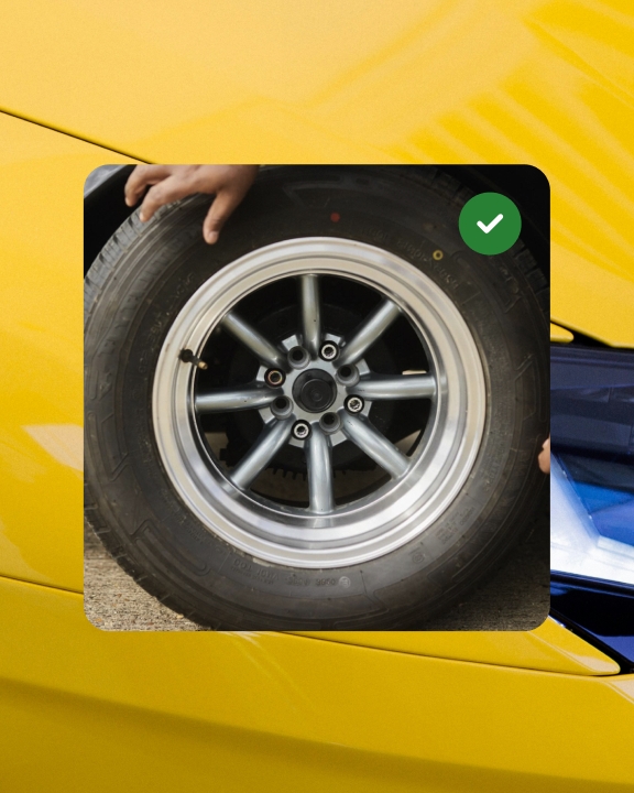 A full bleed card with a car tire and green badge icon in the upper right corner on a full bleed image ad of the hood of a yellow car.