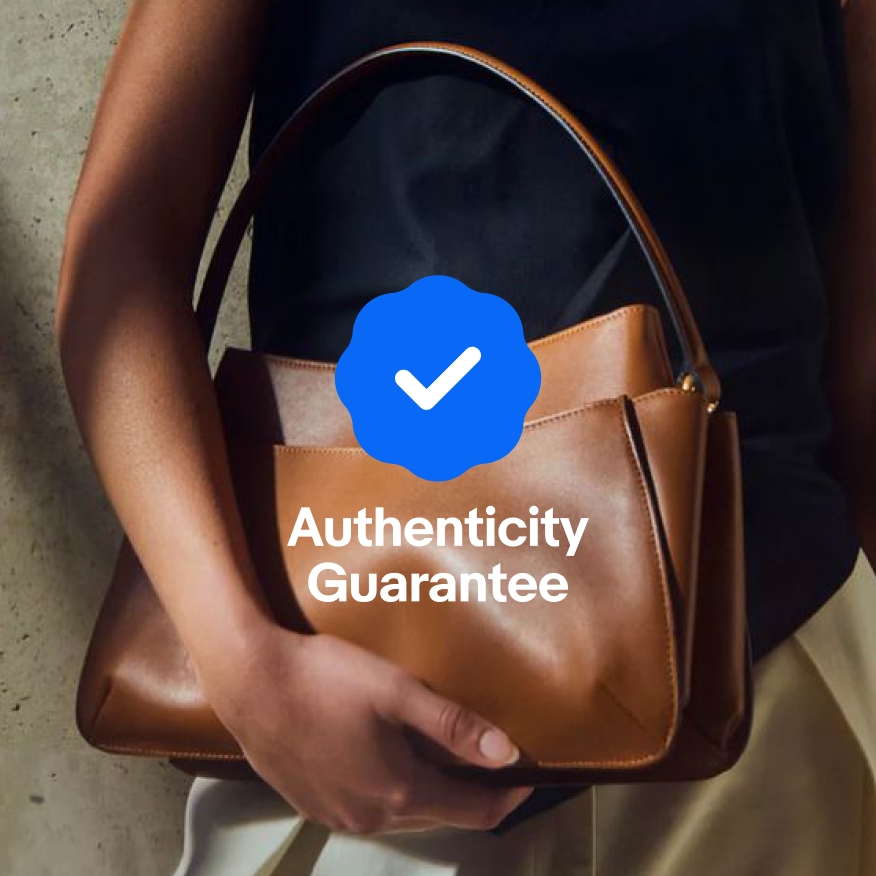 A full bleed image of a woman holding a brown leather handbag under her arm. An Authenticity badge is centered on the image to where the copy under the badge is directly over the brown of the handbag.