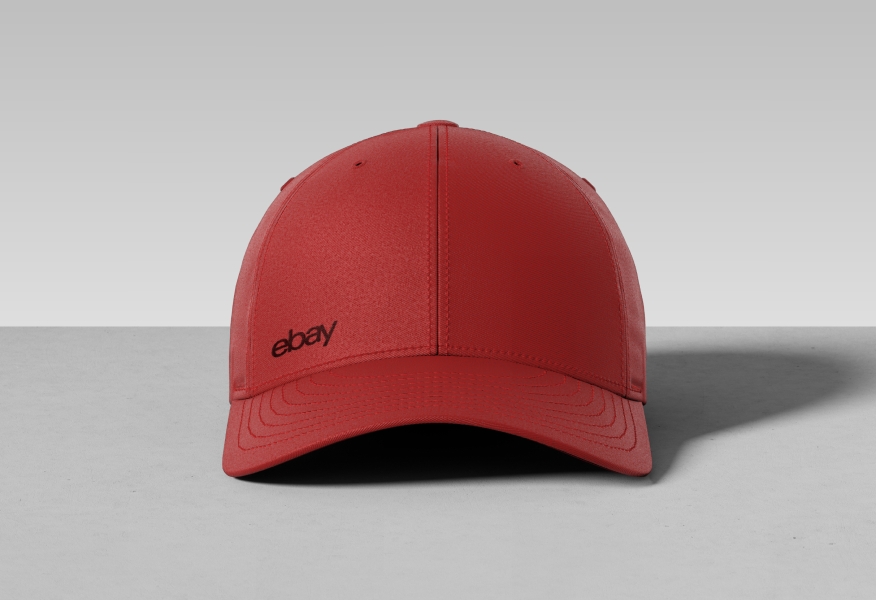 A red baseball hat with a tonal dark red eBay logo embroidered on the left side above the cap.
