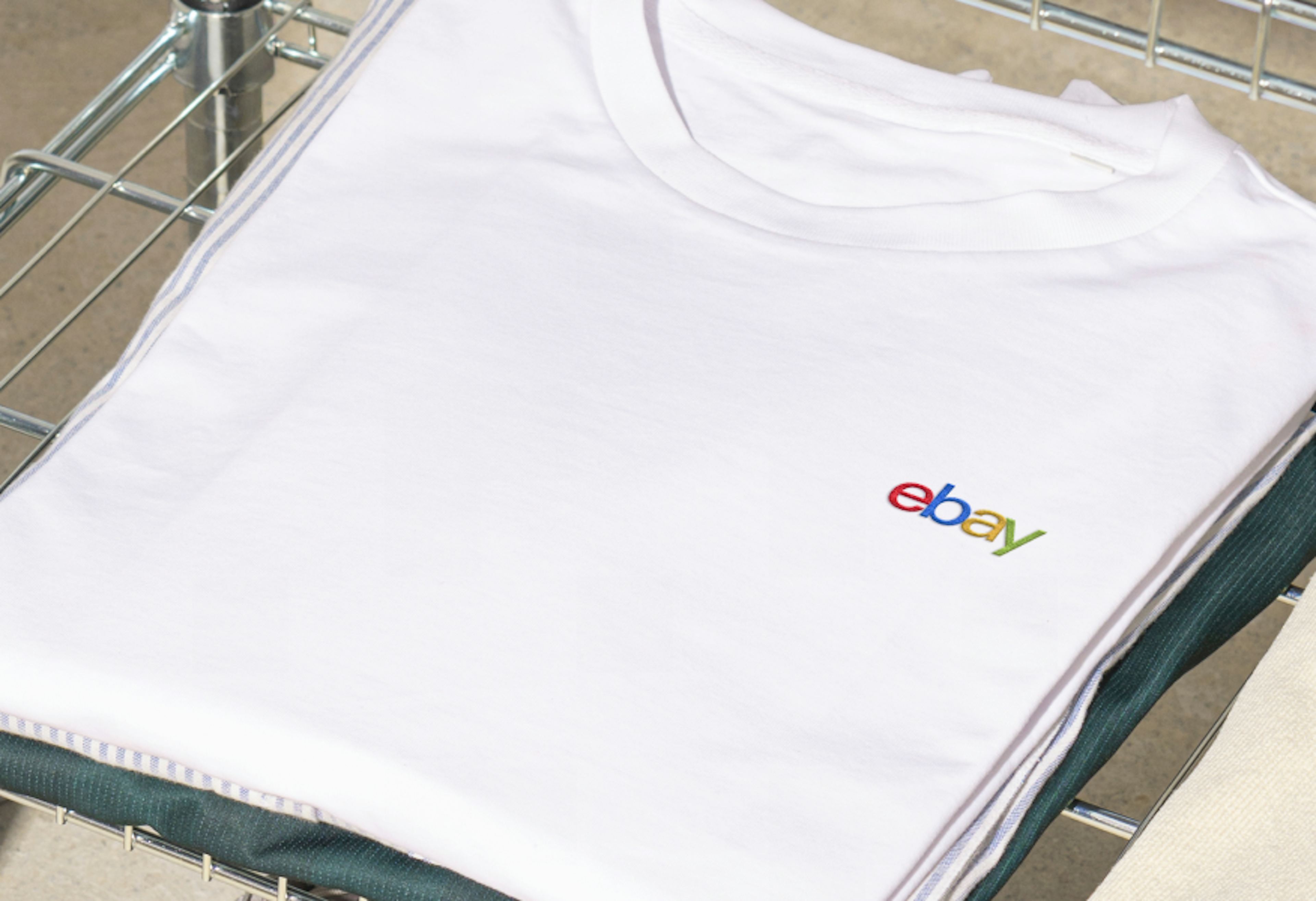 A folded white shirt showcasing the 4-color eBay logo embroidered on the left chest area.