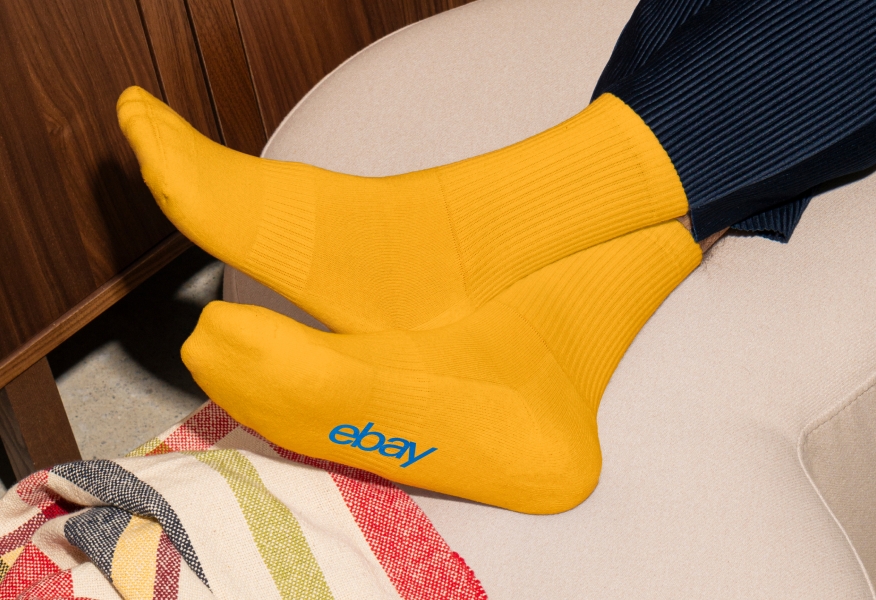 A pair of yellow crew socks with the heritage blue eBay logo.