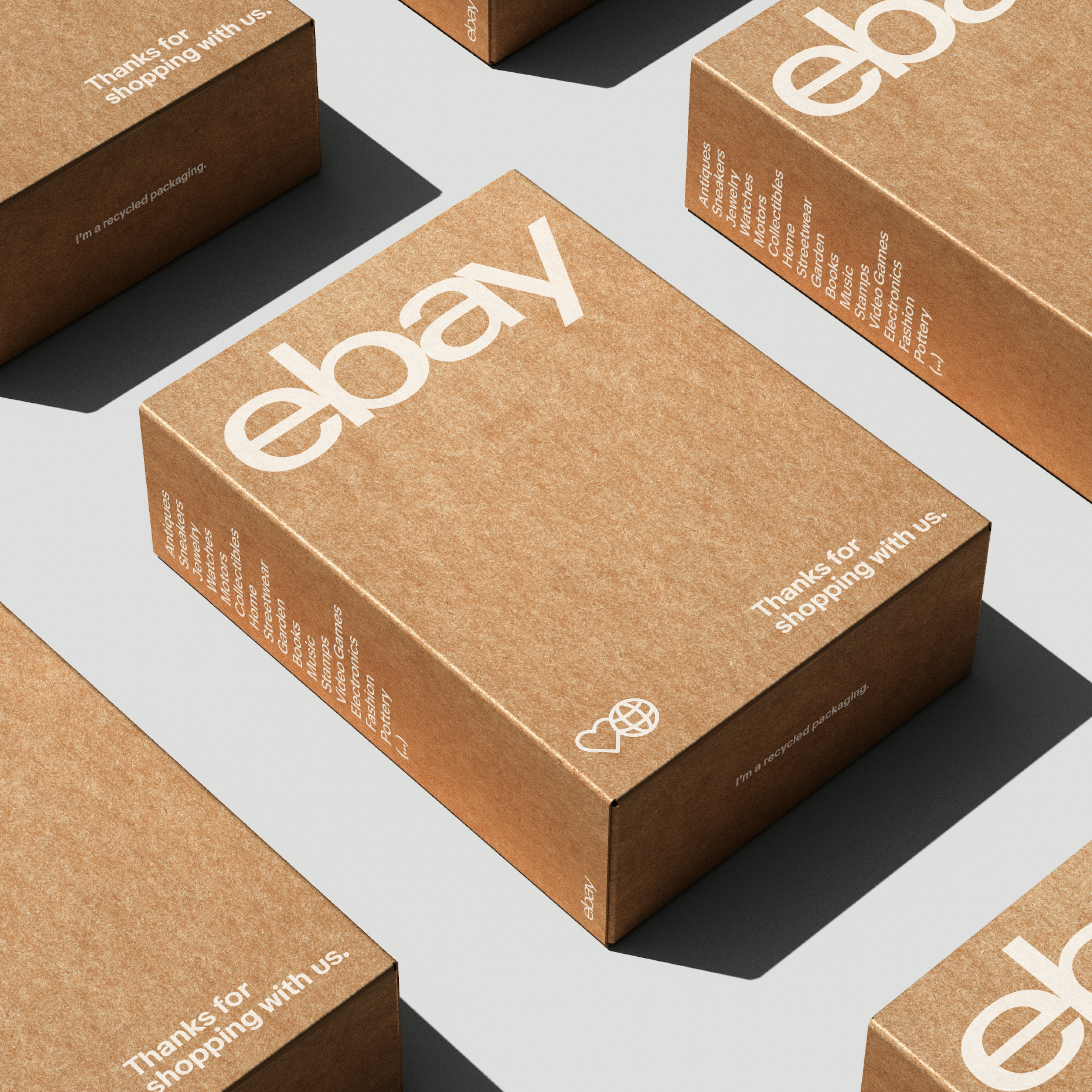 eBay packaging in a grid on a gray table. The boxes are brown cardboard with white type, logo, and icons.