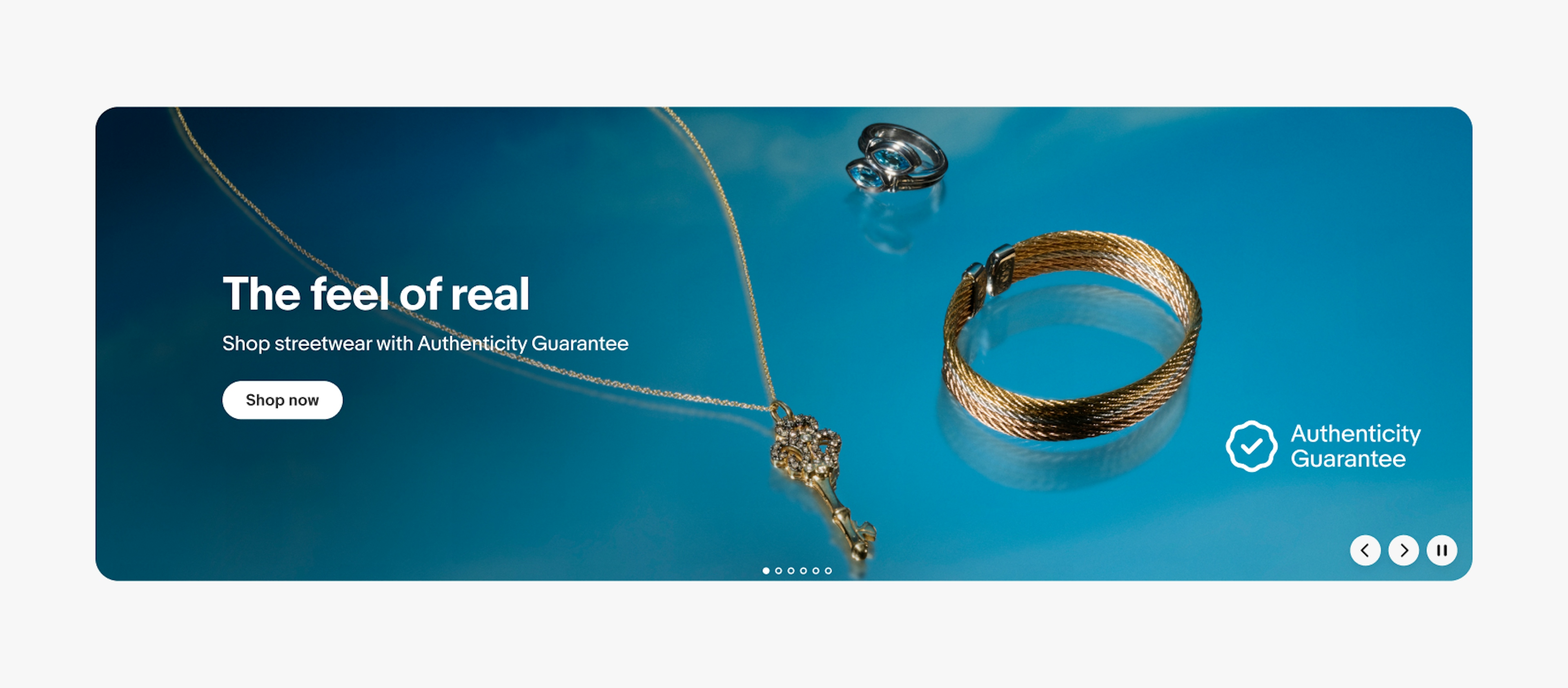 A large product banner with text on the left side containing a headline, subline, and cta button. The image contains a vibrant blue background with 3 types of jewelry. The program badge is randomly placed on the right side of the banner.