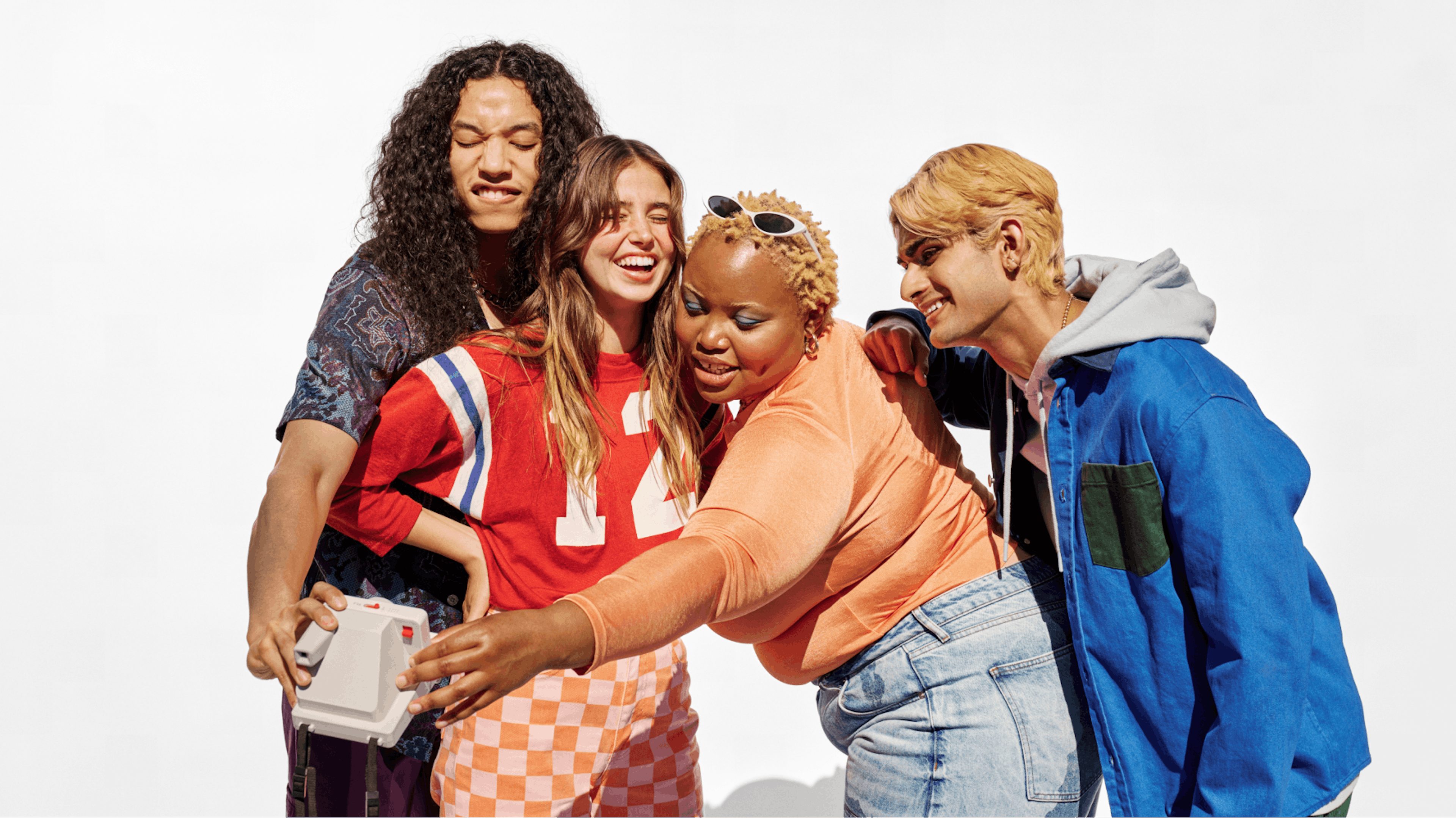 Four friends posing for a selfie, smiling and enjoying themselves in casual, colorful outfits.