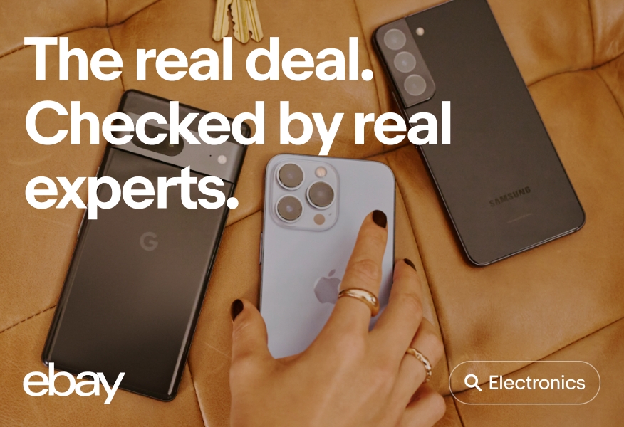 A white outlined ‘Electronics’ UI Element with a white search icon sits on the bottom right of an image of three smartphones sitting on brown leather surface, while a person wearing gold rings and black nail polish reaches for the middle smartphone.