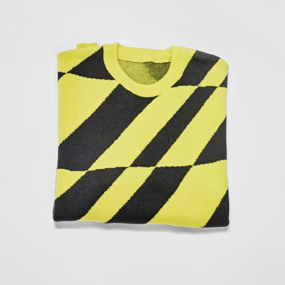 A folded sweater with a yellow and black diagonal stripe pattern with natural shadow.