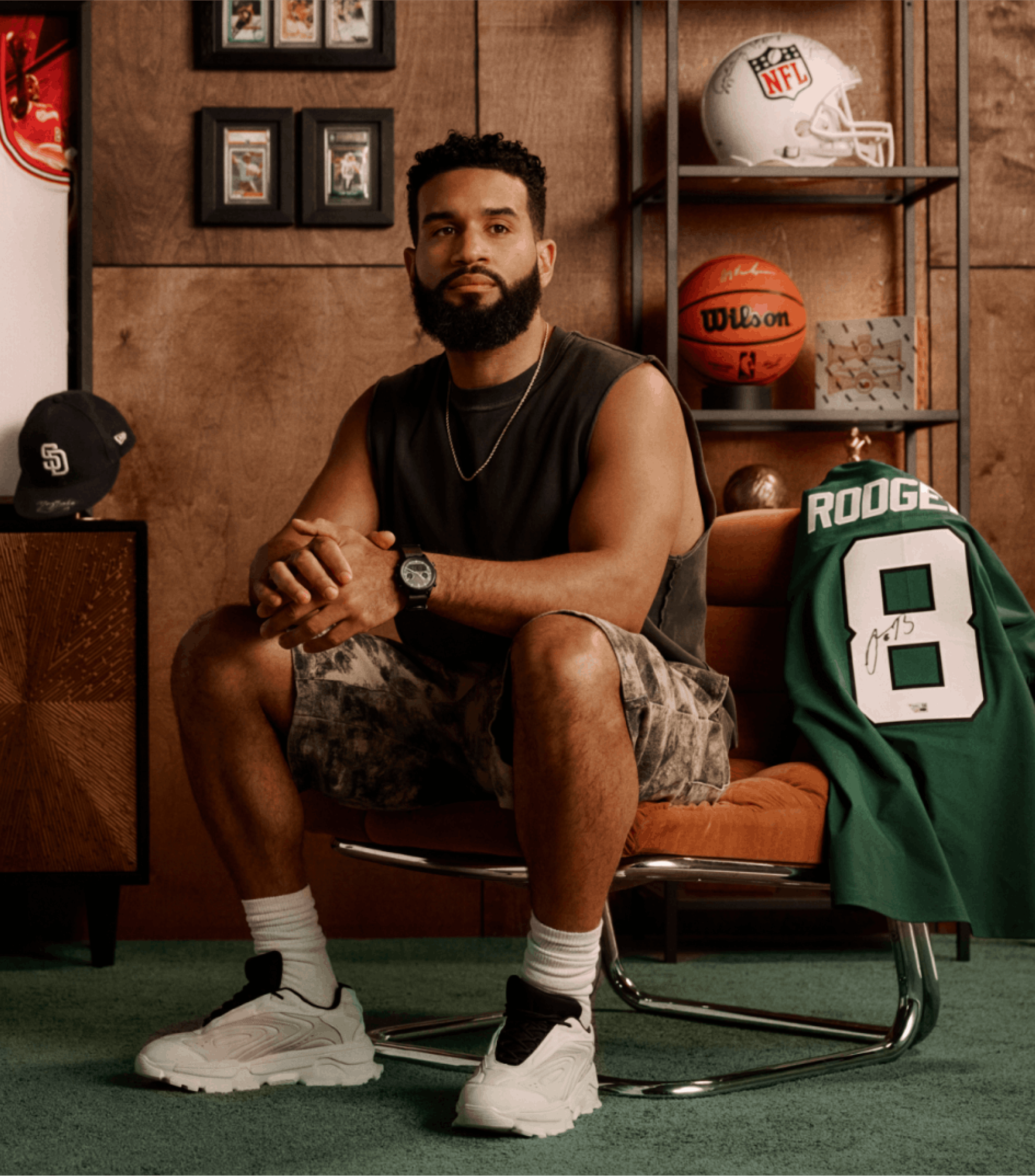 A man sitting in front of sports memorabilia across the back wall.