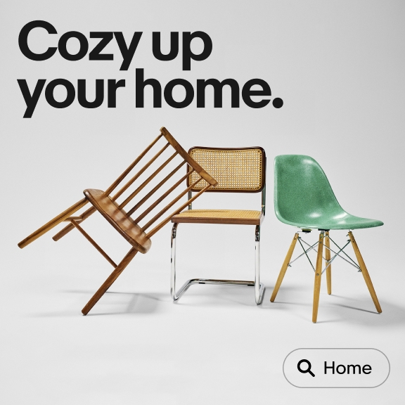 The image features a layout with three different styles of chairs: a wooden spindle-back chair leaning against a cane chair with a metal frame, and a green plastic molded chair with wooden legs. The text above them reads "Cozy up your home," and there is a search icon labeled "Home" at the bottom.