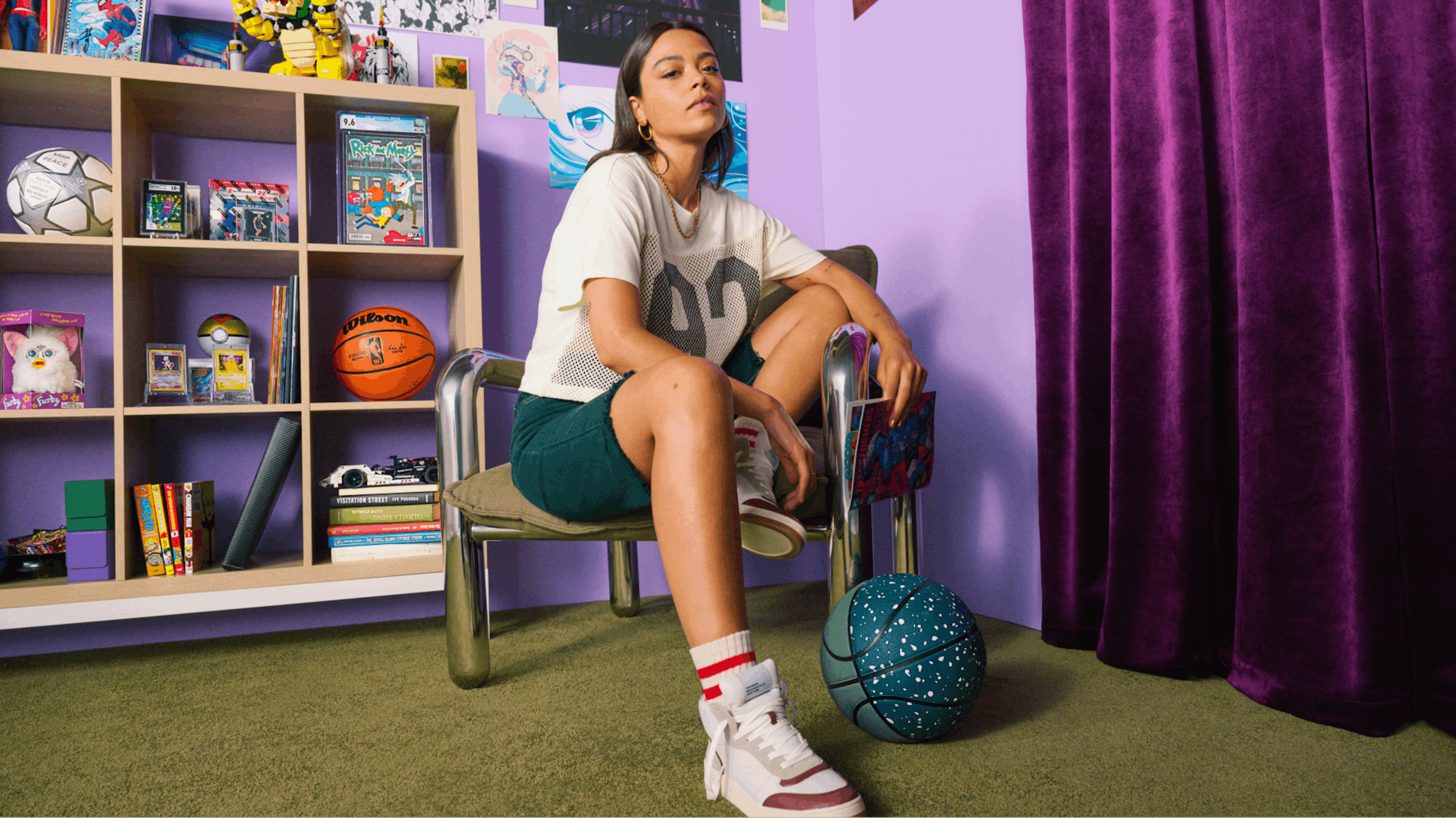 The image shows a young collector in their bedroom sitting on a metal chair. They have a look of confidence as they stare at the camera surrounded with rare collectibles and holding a comic book in their left hand.