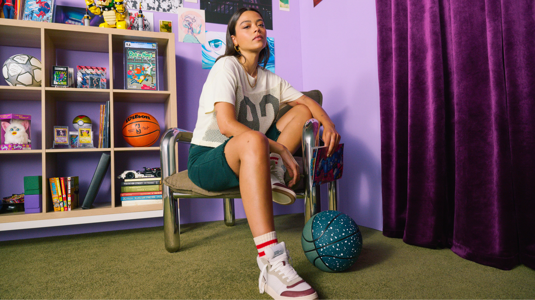 The image shows a young collector in their bedroom sitting on a metal chair. They have a look of confidence as they stare at the camera surrounded with rare collectibles and holding a comic book in their left hand.