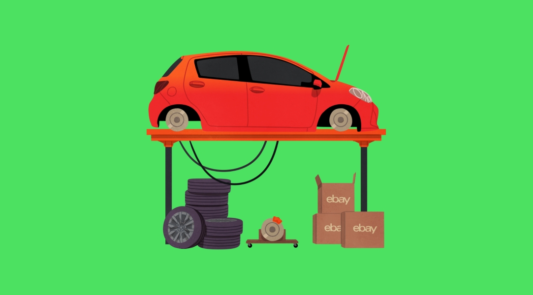 A small red car raised on a mechanic lift with a stack of tires, car parts and open ebay boxes on the floor underneath.