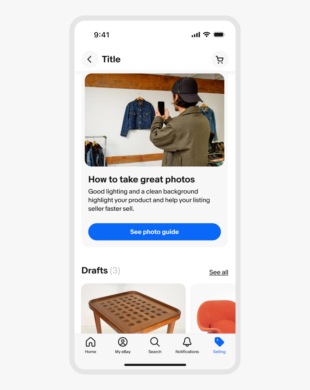A phone screen titled “Selling” with a vertical card with a light grey background. The card has a photo of two people taking a photo of a jacket, a title labeled “How to take great photos”, body copy, and a primary CTA button labeled “See photo guide”. Below is a section labeled “Drafts (3)” with two images.