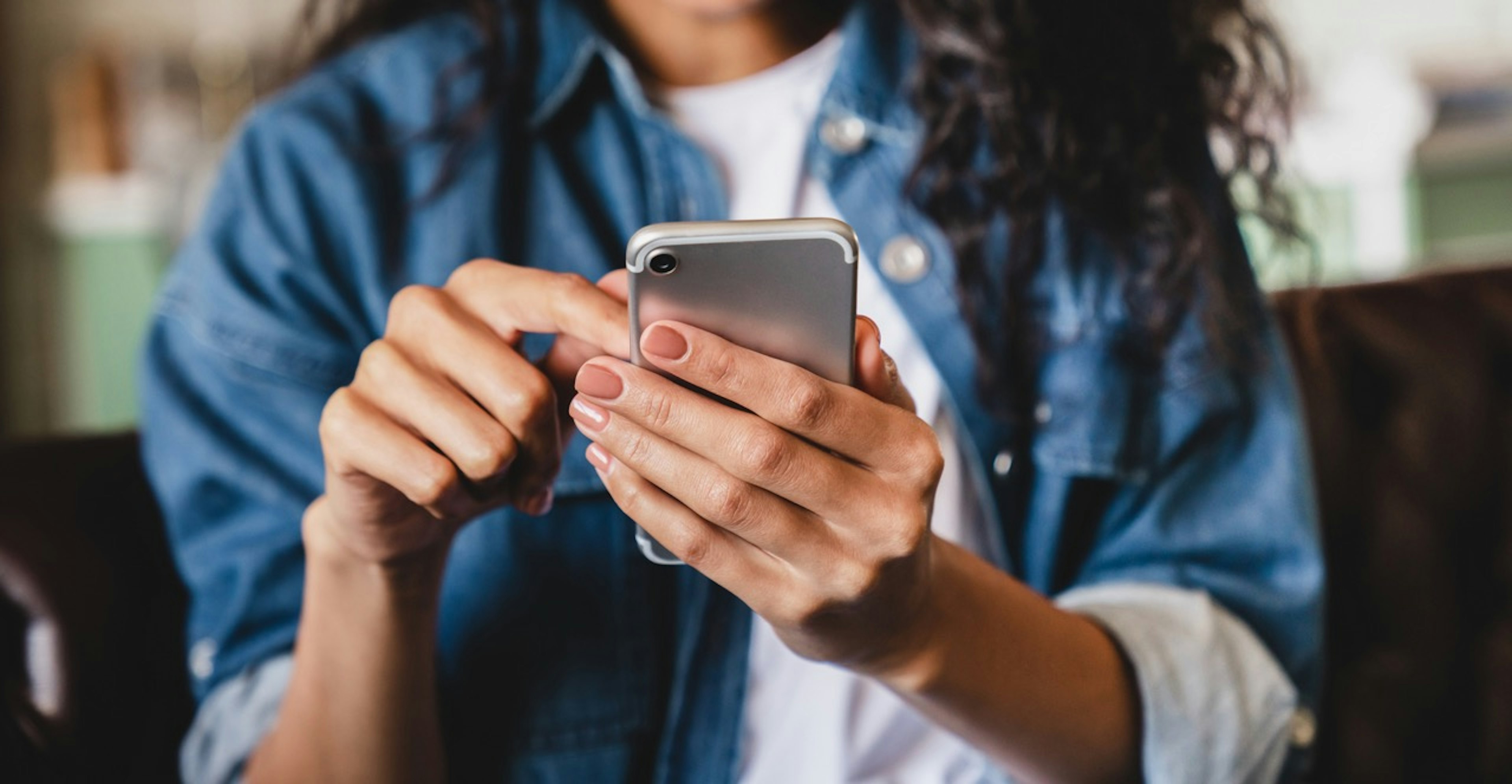 Person using a smartphone, navigating a mobile app with one hand while seated indoors.