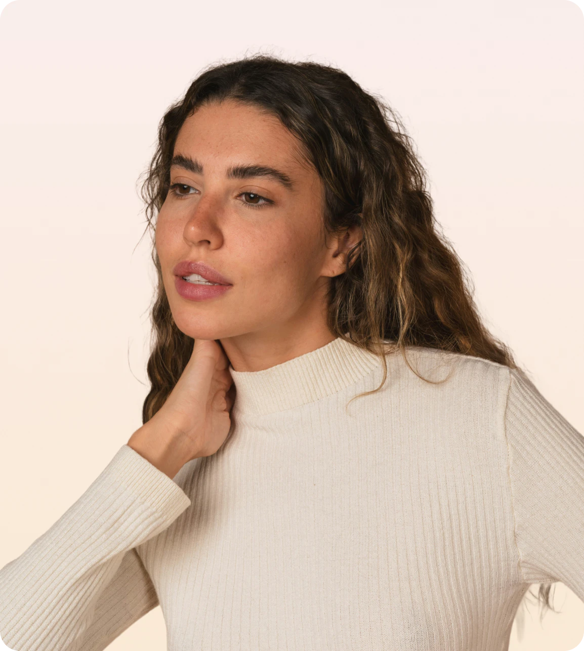 A woman in a cream turtleneck resting a hand at her neck
