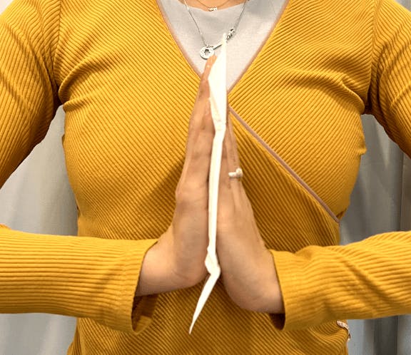 A woman wearing an orange top holds a Daye pad in between her hands 