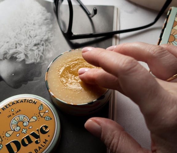a finger is touching the Daye balm and showing the consistency of the product
