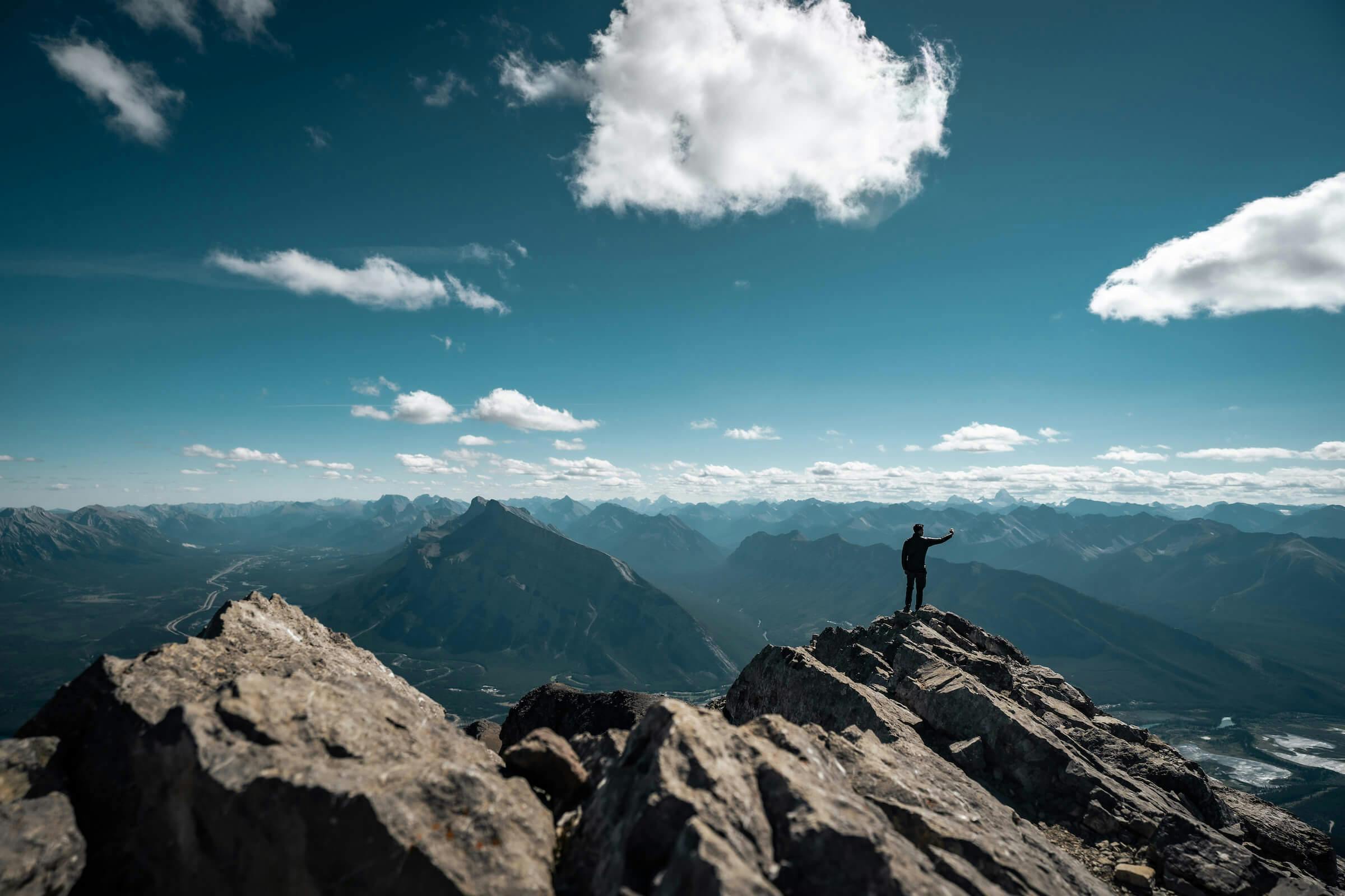 A climber takes a selfie on top of a rocky mountain