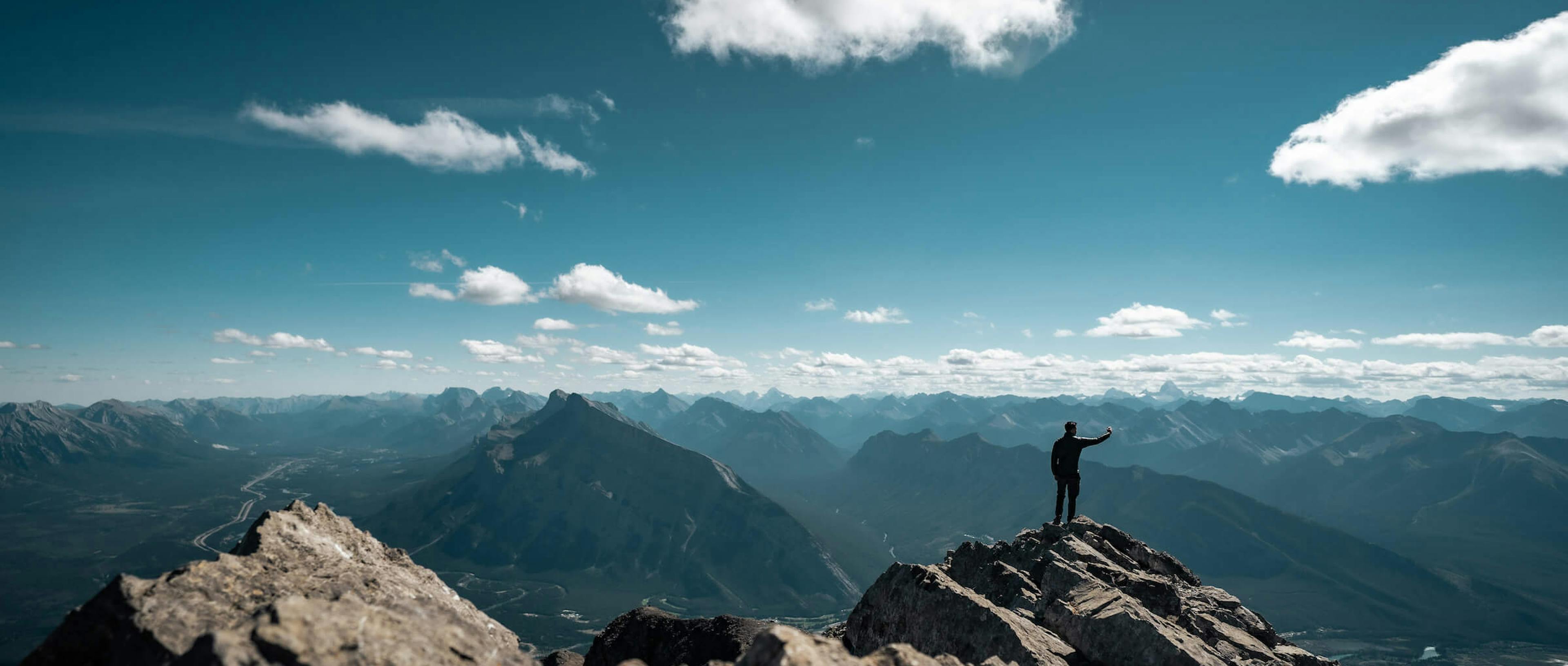 A climber takes a selfie on top of a rocky mountain