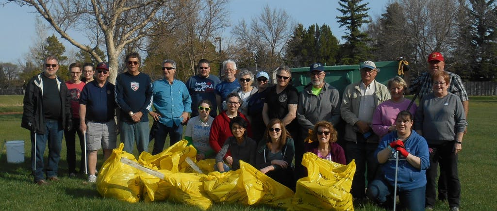 Large group of people together in front of yellow garbage bags.