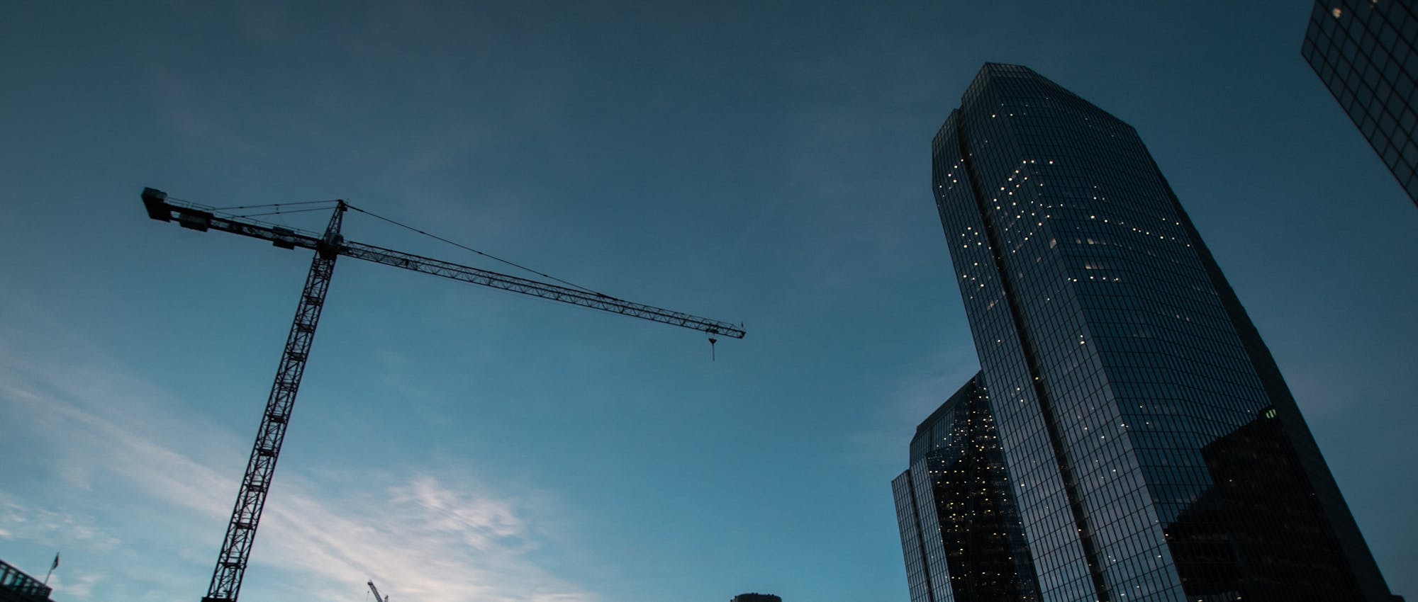 A crane and skyscraper against a blue evening sky