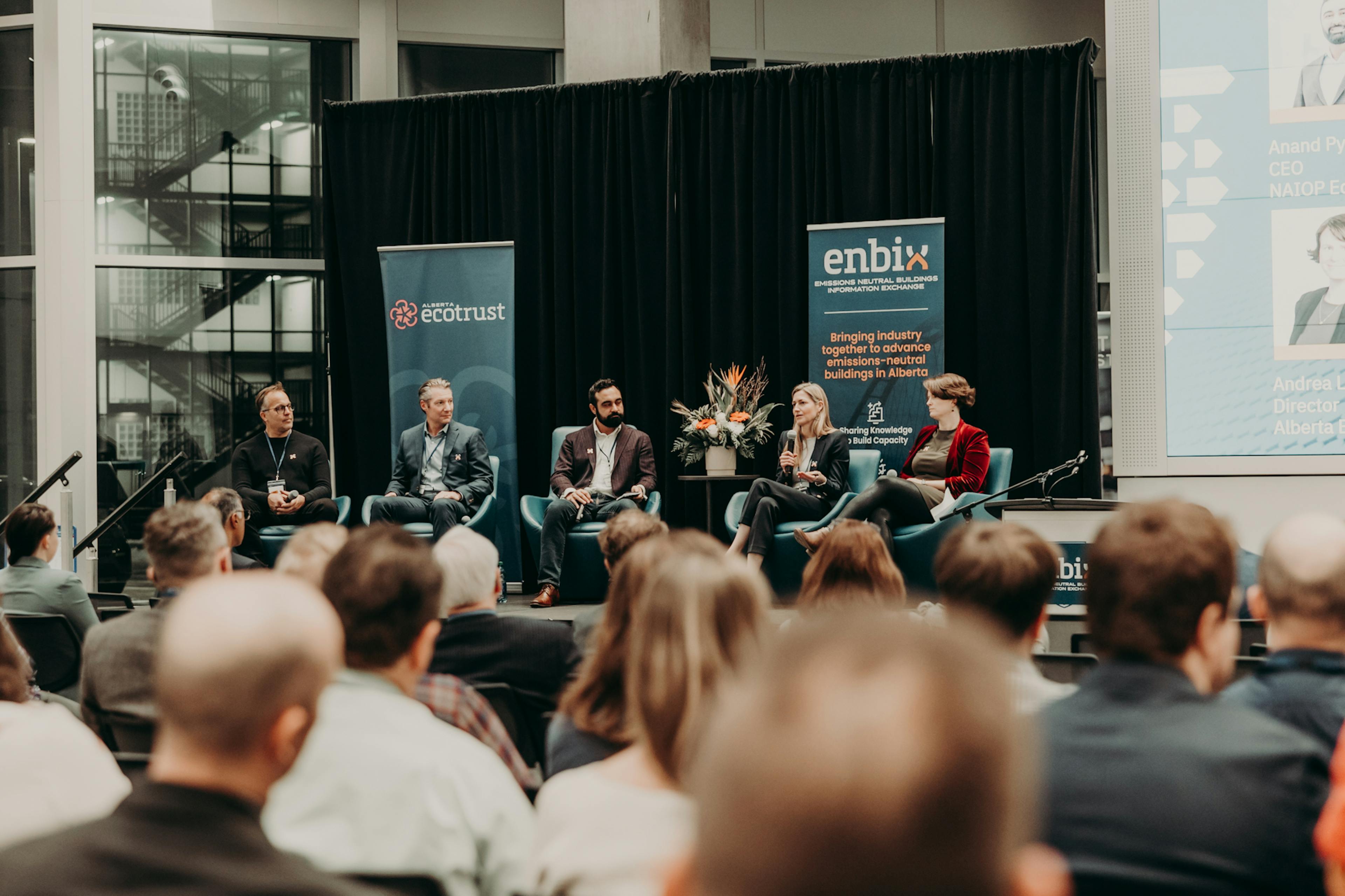 Five panelists in front of a crowd on stage