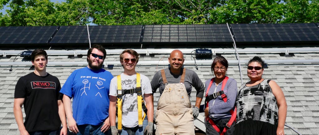 Group of people standing in front of a rooftop solar system